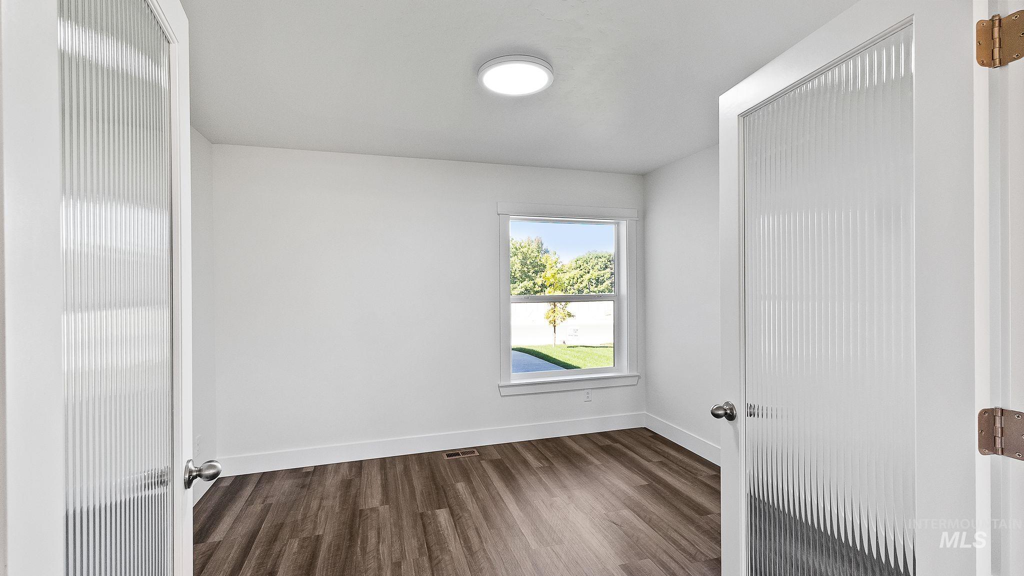 Empty room with dark wood finished floors and baseboards