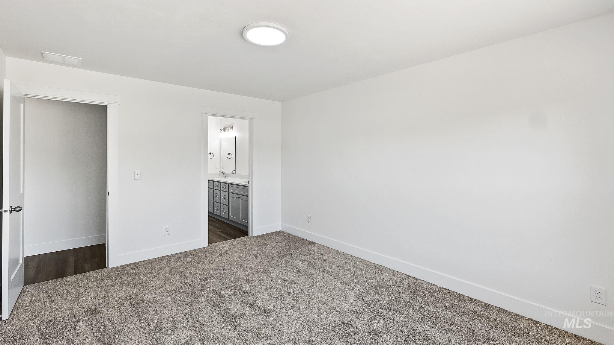 Unfurnished bedroom with dark colored carpet and connected bathroom