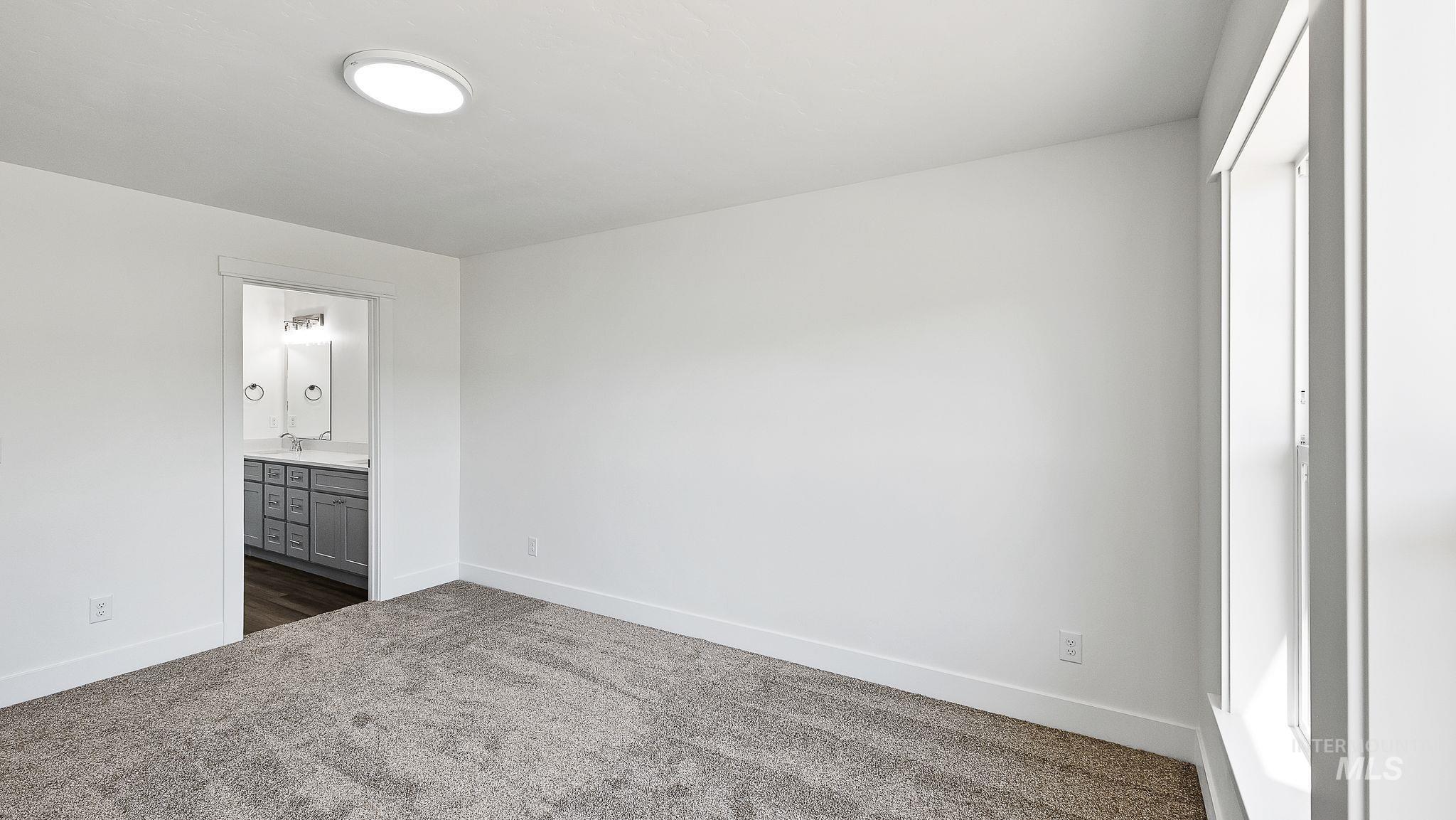 Unfurnished bedroom with dark colored carpet and ensuite bath