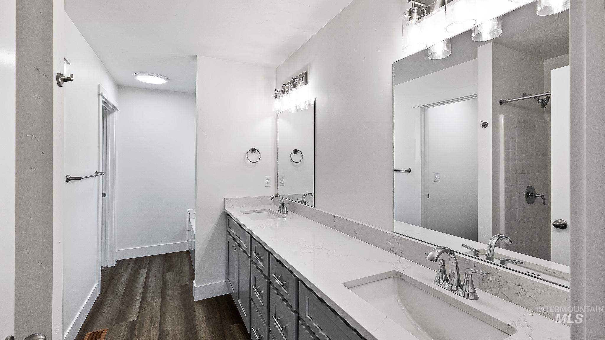 Bathroom with double vanity and dark wood-type flooring