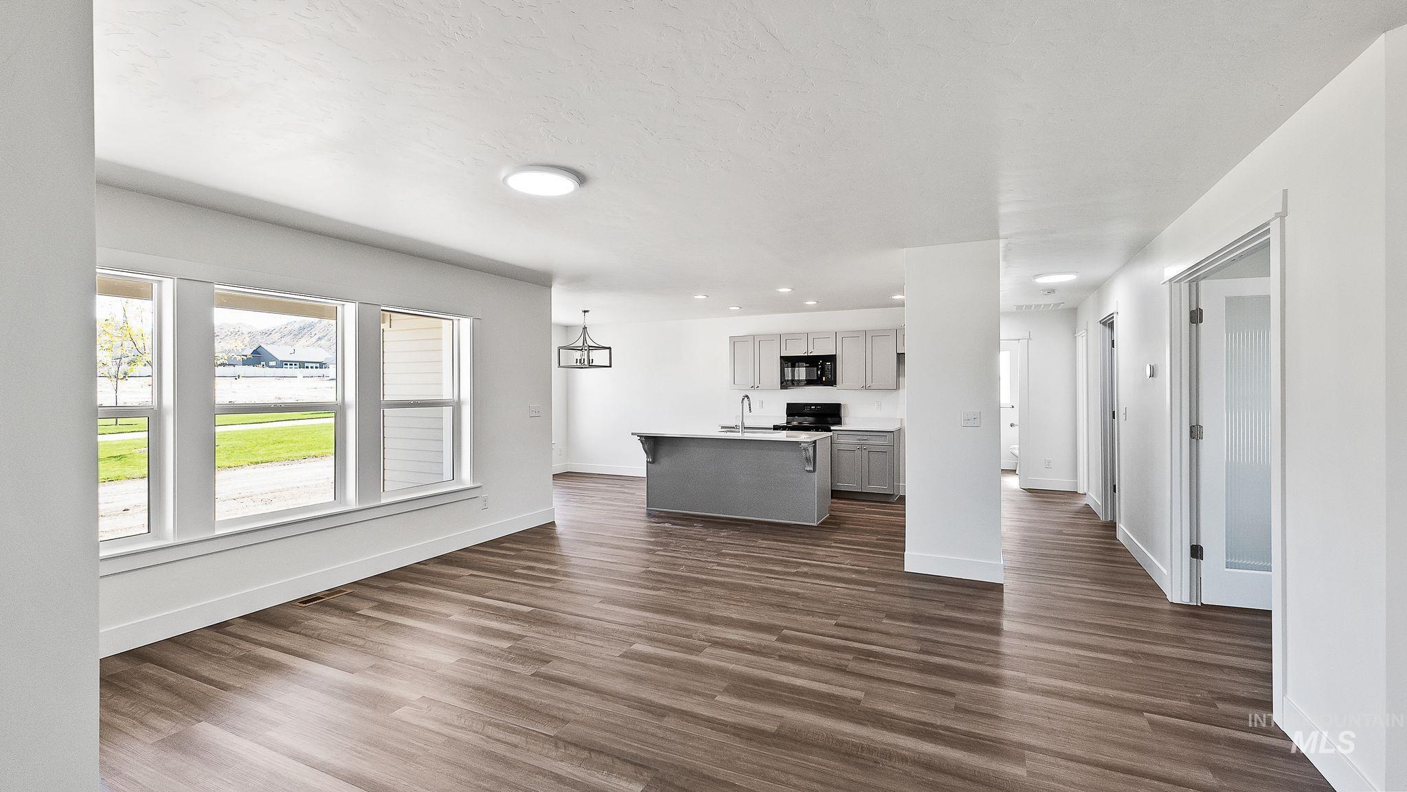 Unfurnished living room featuring dark wood-type flooring, a textured ceiling, and recessed lighting