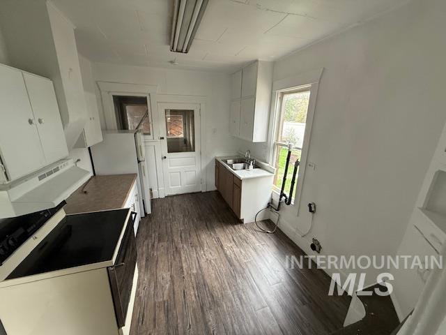 Kitchen featuring white cabinetry, electric stove, freestanding refrigerator, and dark wood finished floors