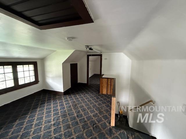 Bonus room featuring dark colored carpet and lofted ceiling
