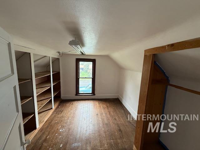 Bonus room featuring lofted ceiling, hardwood / wood-style floors, and a textured ceiling