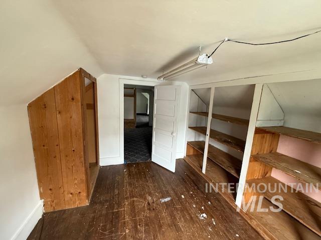 Bonus room featuring dark wood-style flooring and vaulted ceiling