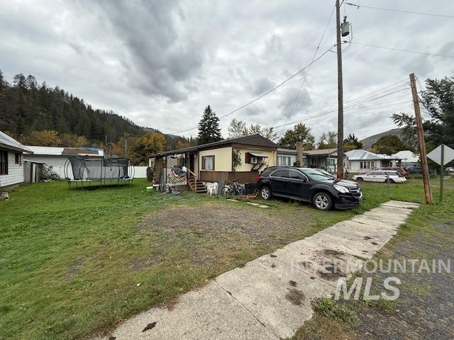 View of front of property featuring a trampoline and a front lawn