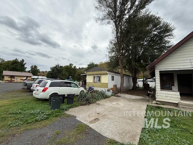 View of side of property with driveway and a lawn