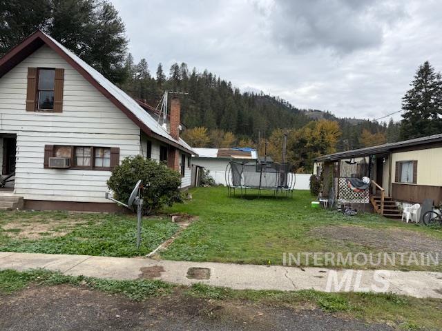 View of home's exterior featuring a trampoline, a yard, and a chimney