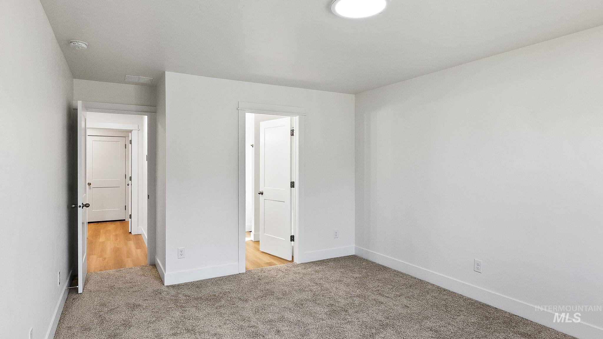 Unfurnished bedroom with light colored carpet and baseboards