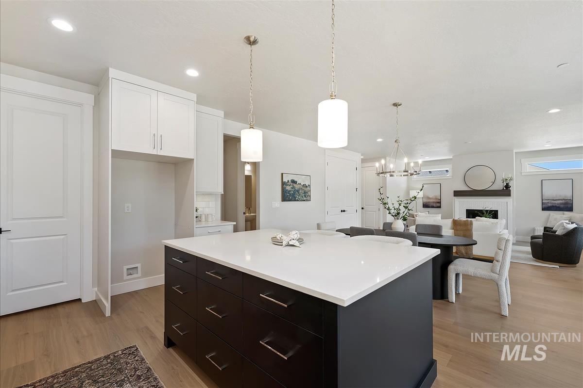 Kitchen featuring white cabinets, light countertops, light wood finished floors, a kitchen island, and recessed lighting