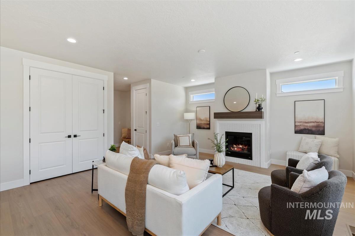 Living room featuring light wood-type flooring, plenty of natural light, a glass covered fireplace, and recessed lighting