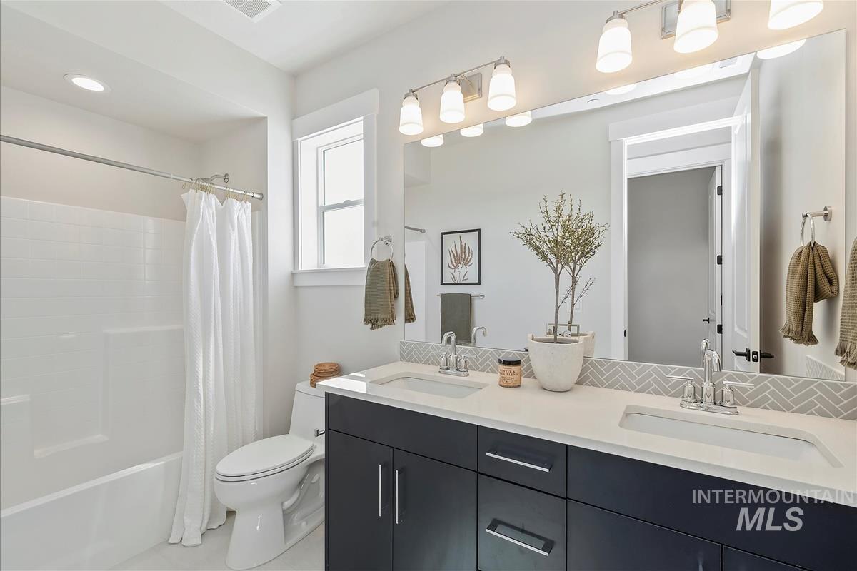 Bathroom featuring double vanity and shower / tub combo