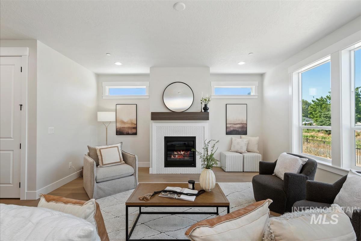 Living room featuring wood finished floors, a glass covered fireplace, and recessed lighting