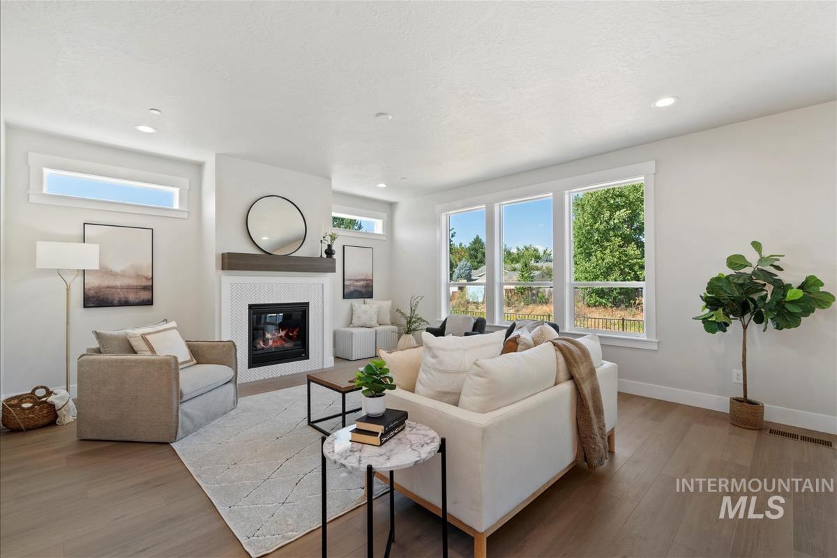 Living room featuring a glass covered fireplace, light wood-type flooring, and recessed lighting