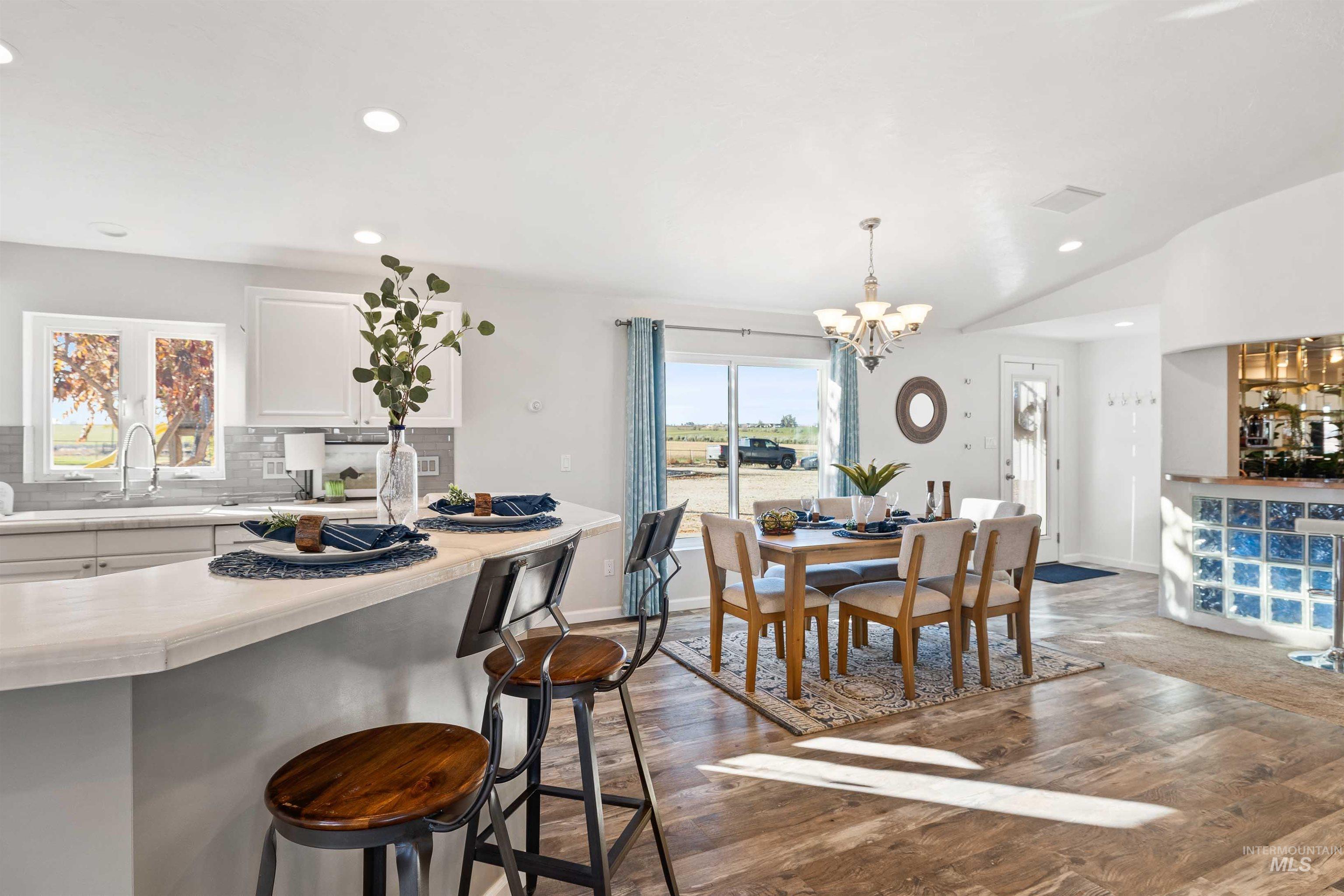 Dining area with dark wood-type flooring, recessed lighting, and a chandelier