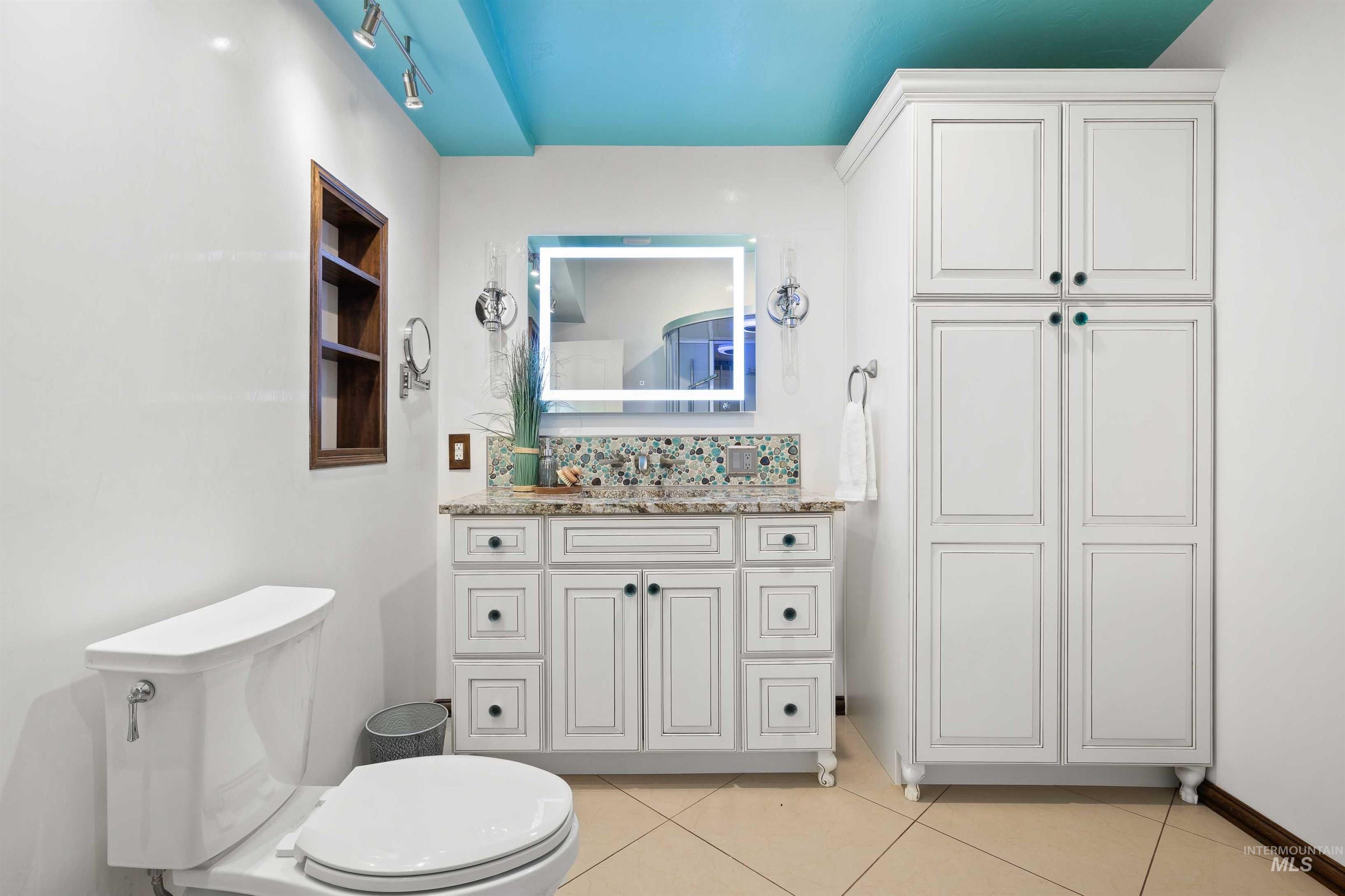 Bathroom with light tile patterned flooring, vanity, and backsplash