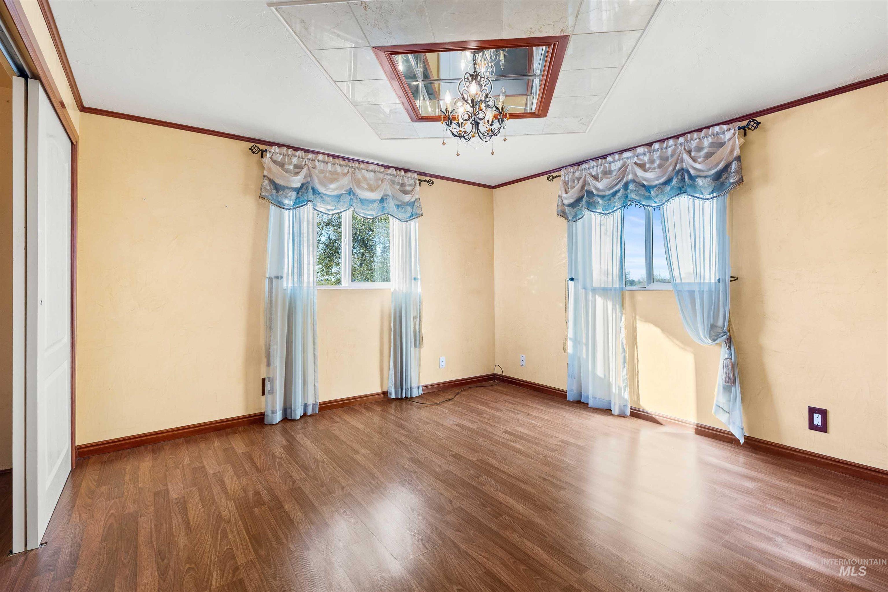 Empty room featuring ornamental molding, a chandelier, and wood finished floors
