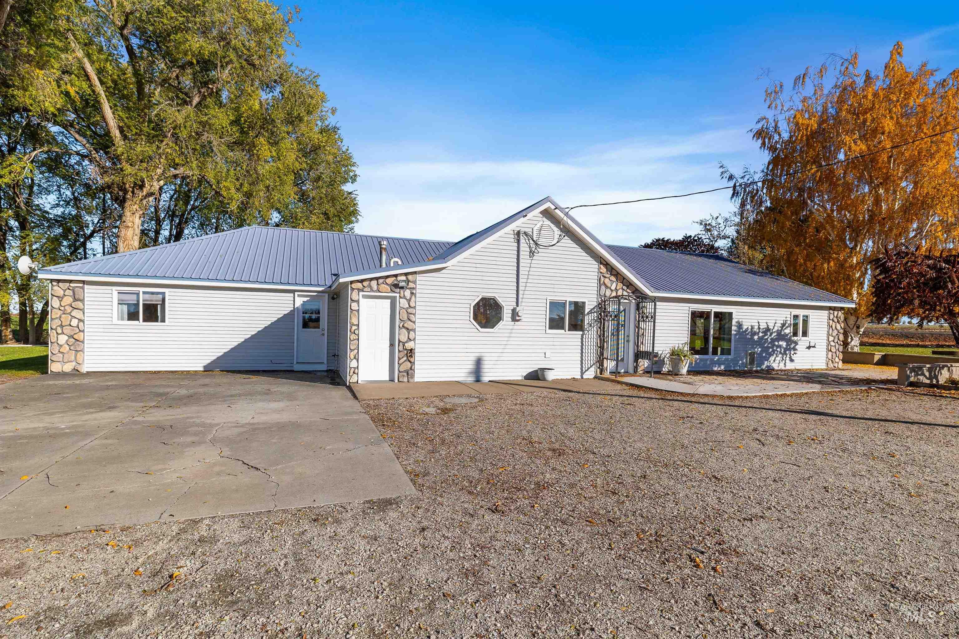 View of front facade featuring stone siding, a metal roof, and a patio