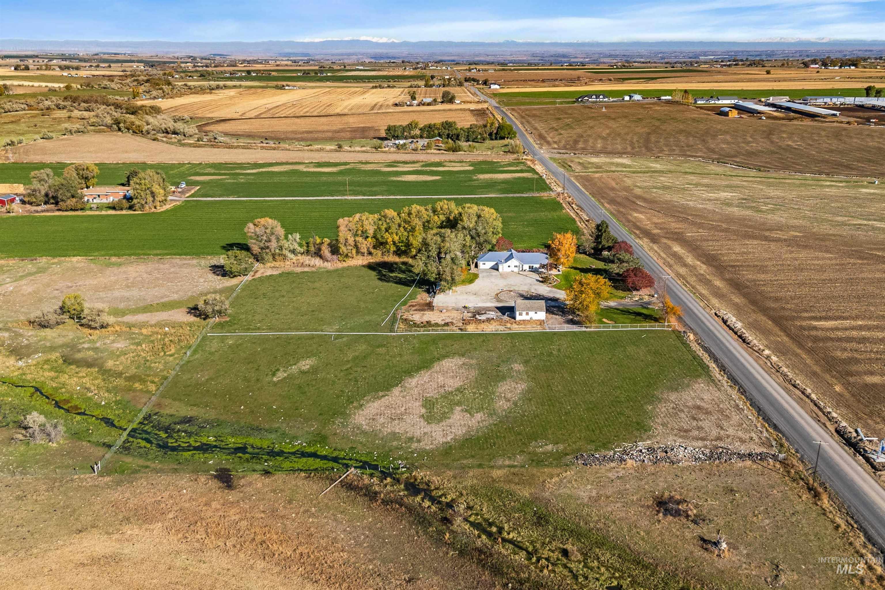 Aerial view of property's location featuring rural landscape, rows of crops, and a mountainous background