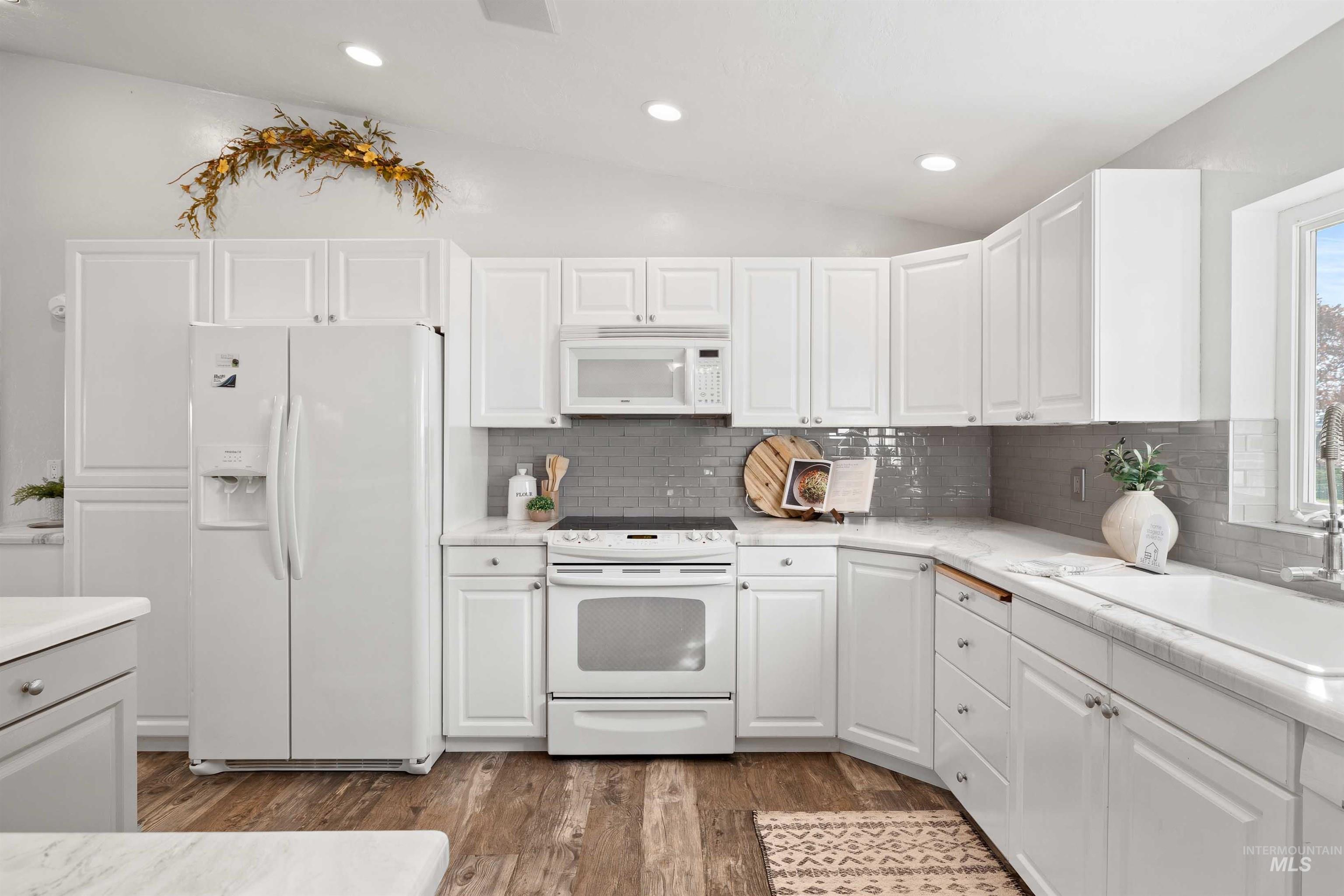 Kitchen with white appliances, white cabinetry, dark wood-style flooring, backsplash, and recessed lighting