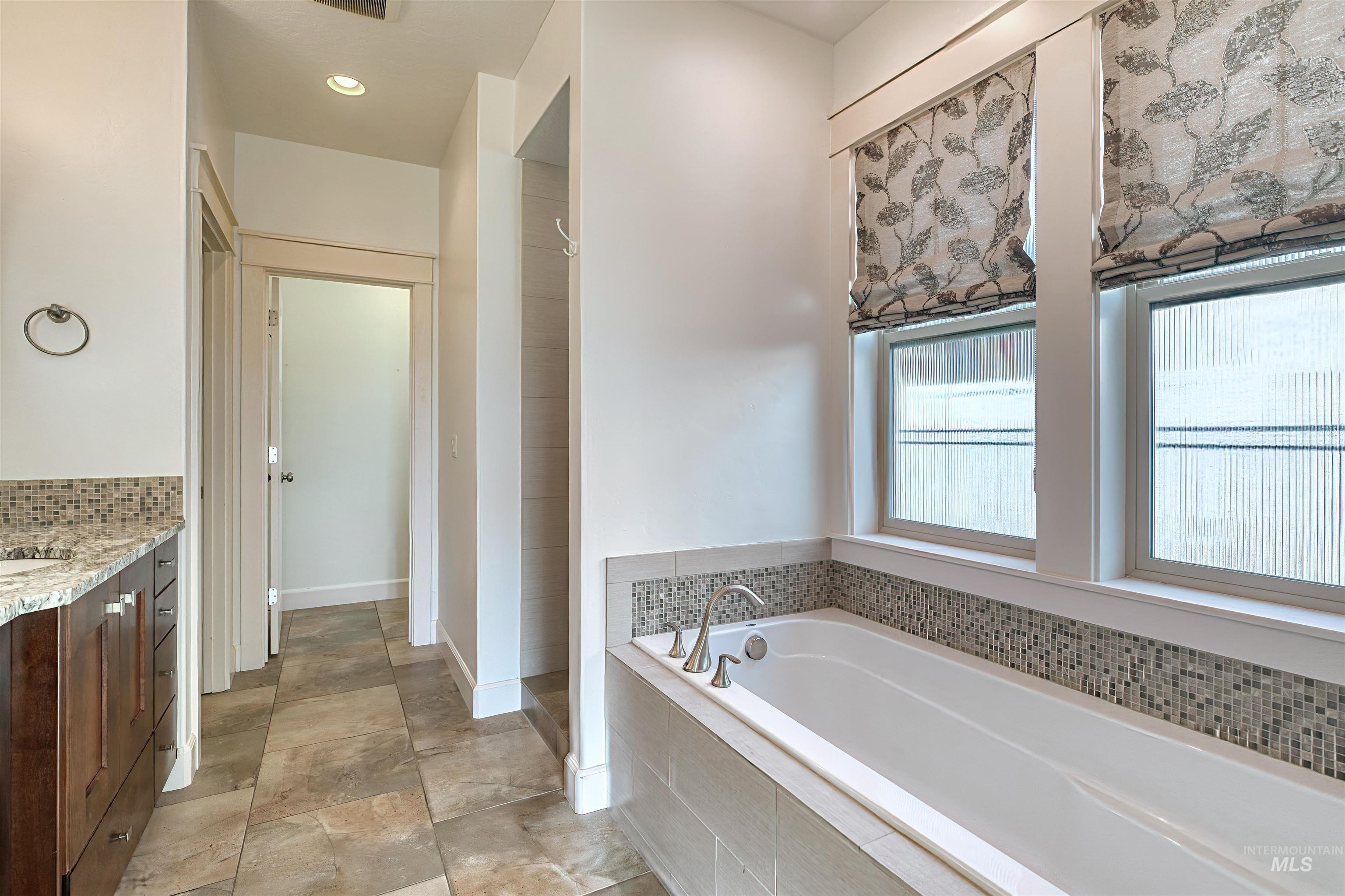 Bathroom with vanity, a garden tub, recessed lighting, and a tile shower
