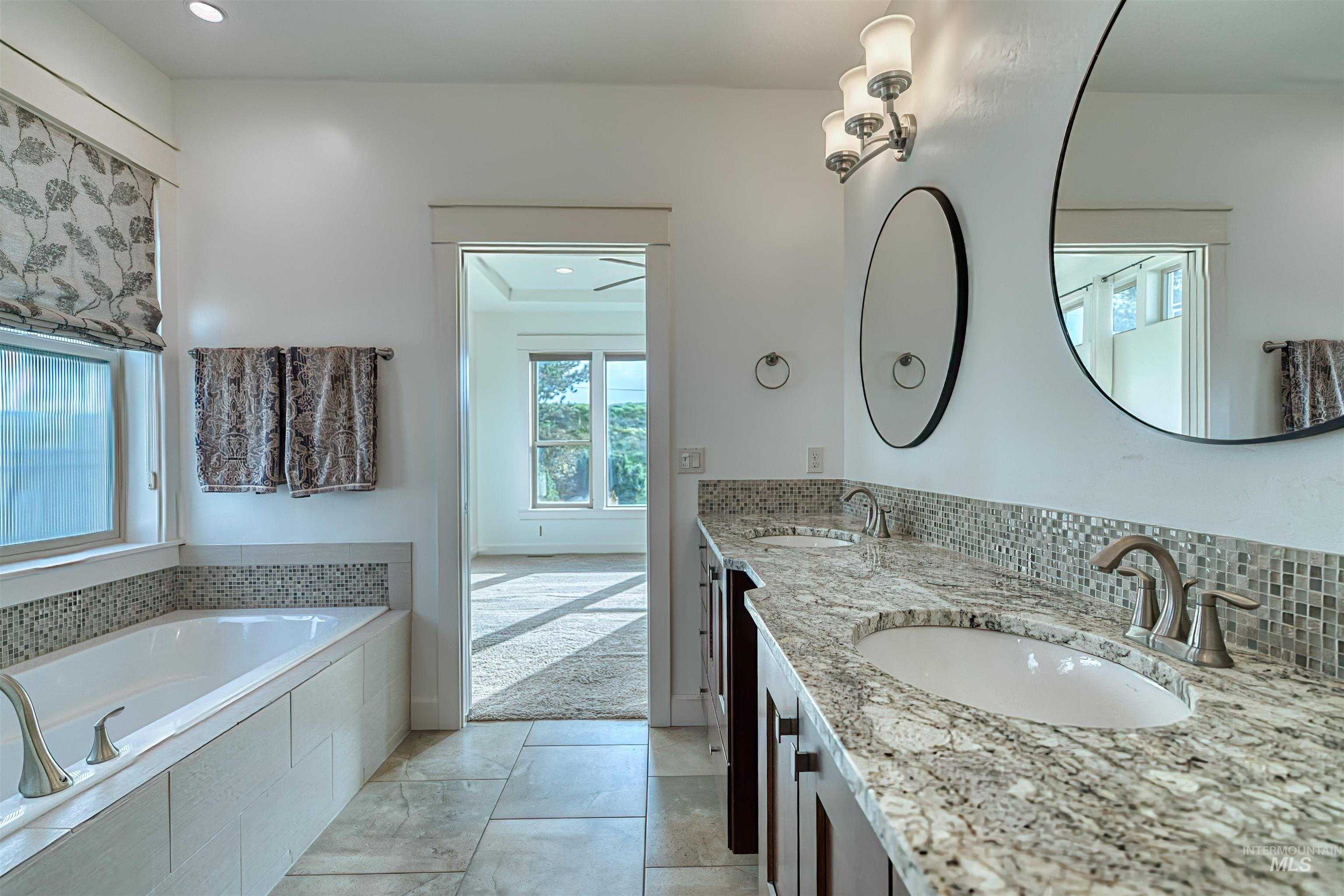 Bathroom with double vanity, a bath, tasteful backsplash, and recessed lighting