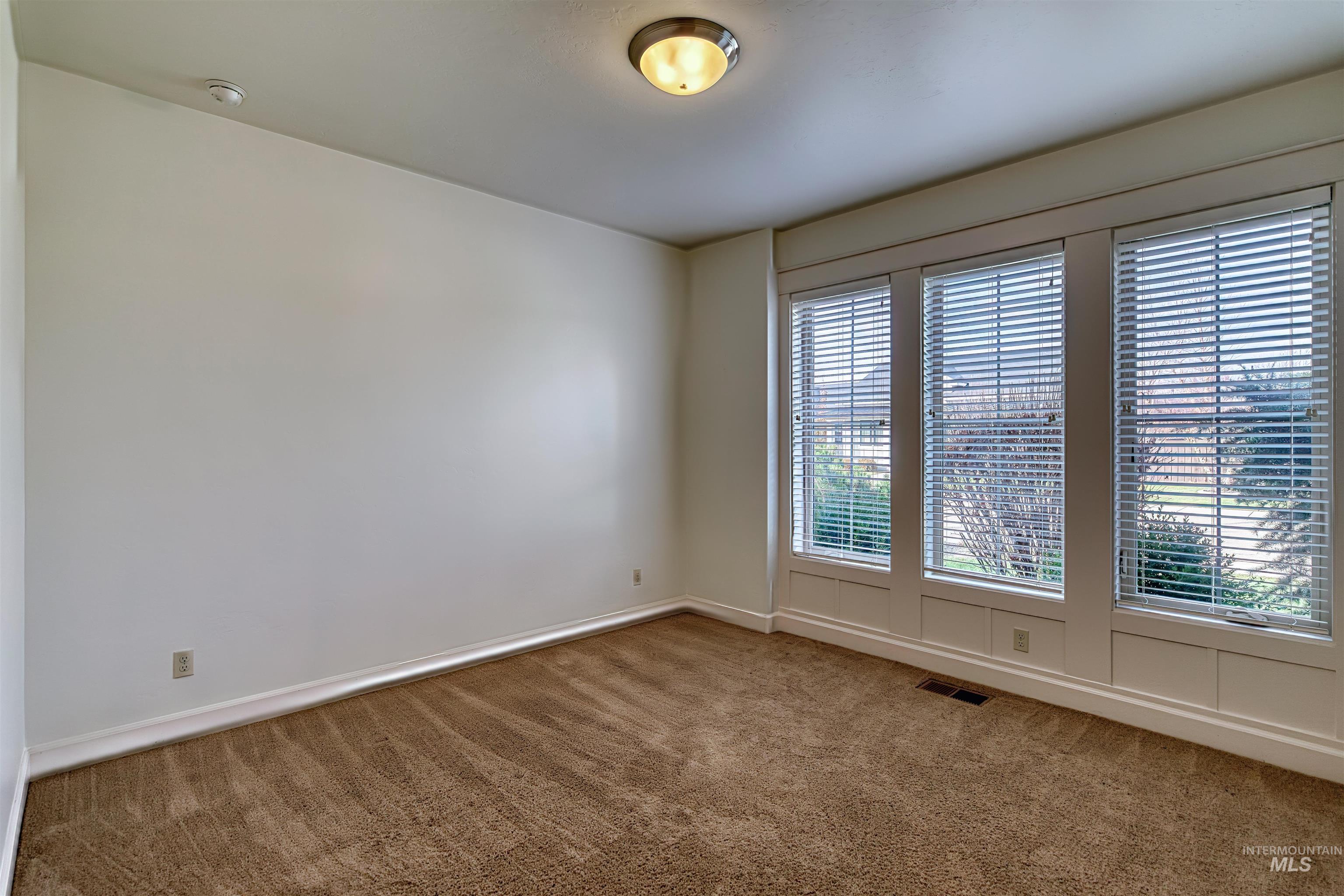Carpeted spare room featuring baseboards