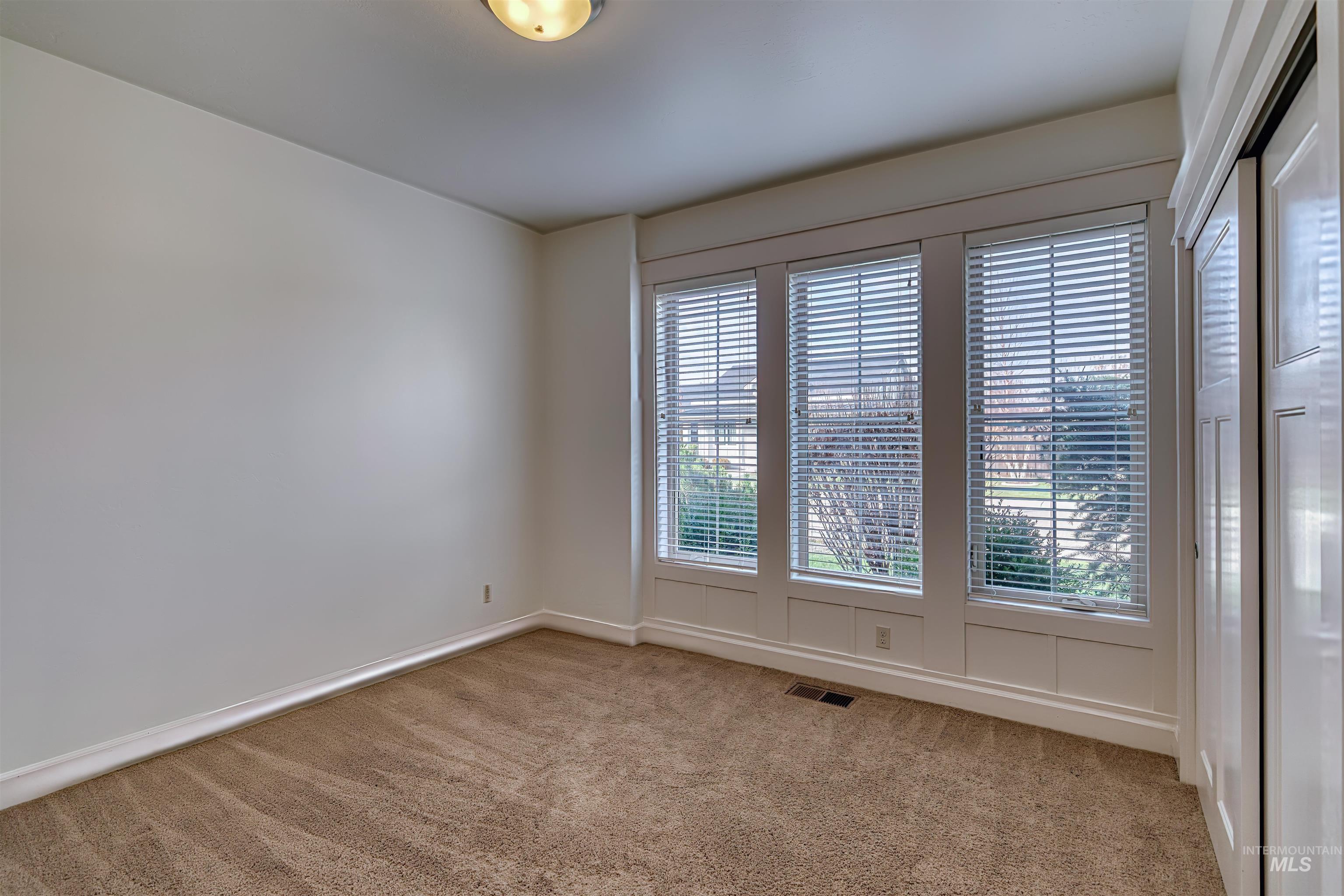 Empty room featuring light colored carpet and baseboards