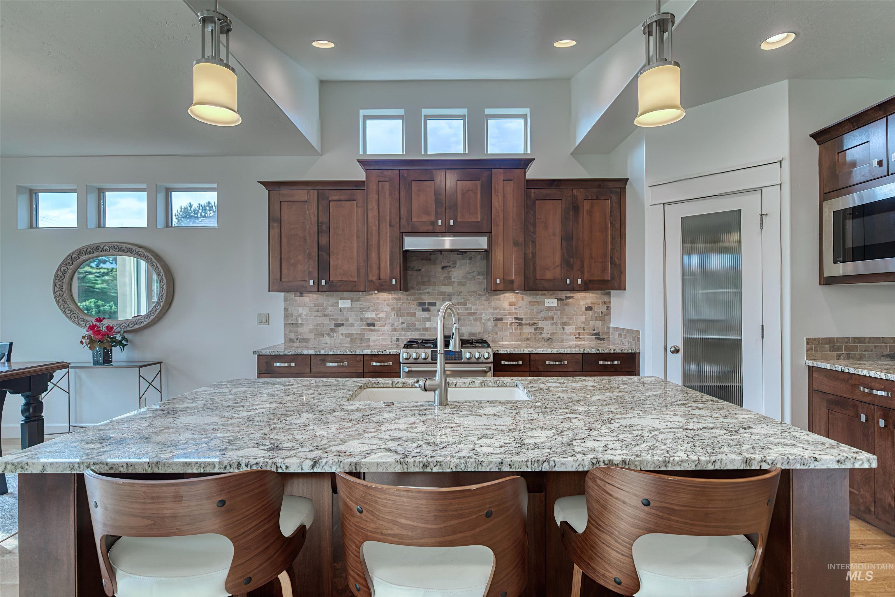 Kitchen featuring light stone countertops, a breakfast bar, decorative backsplash, and recessed lighting