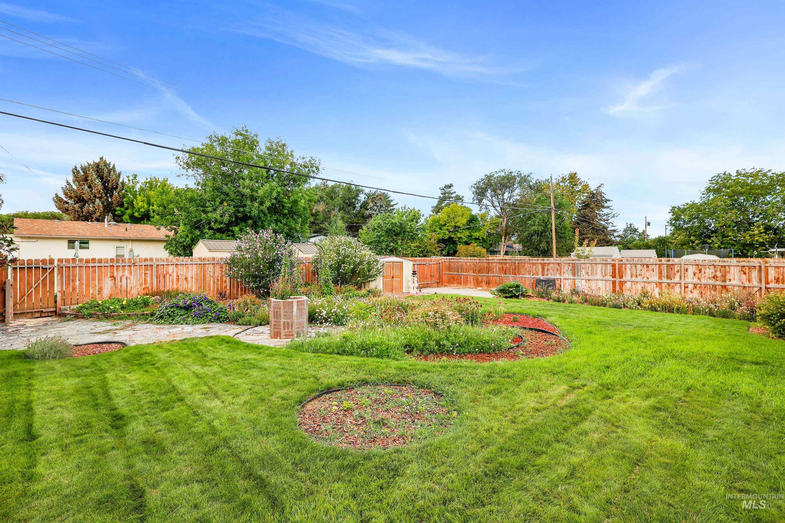 Fenced backyard featuring a storage unit and a patio