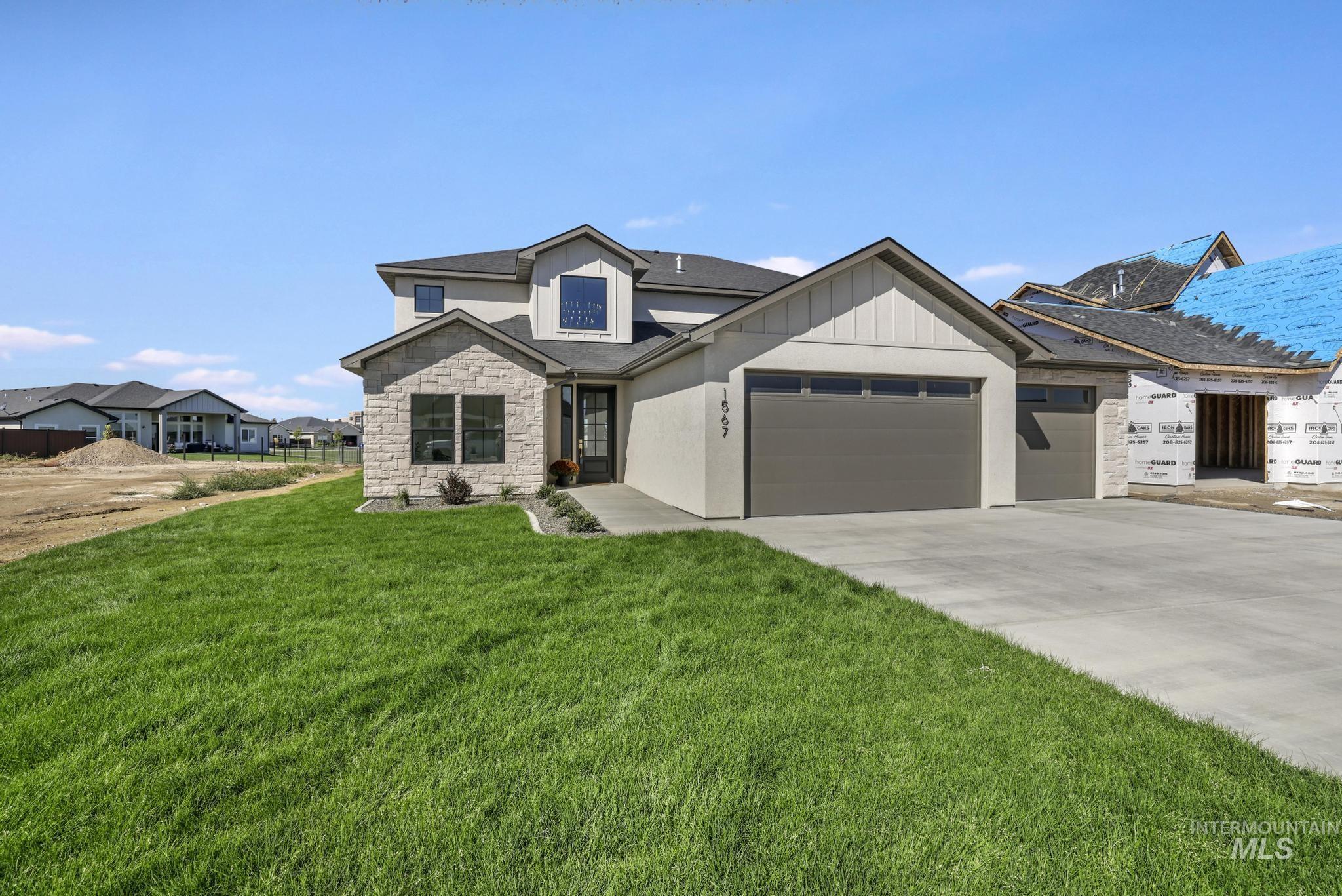 View of front of home with stone siding, concrete driveway, an attached garage, a front lawn, and stucco siding