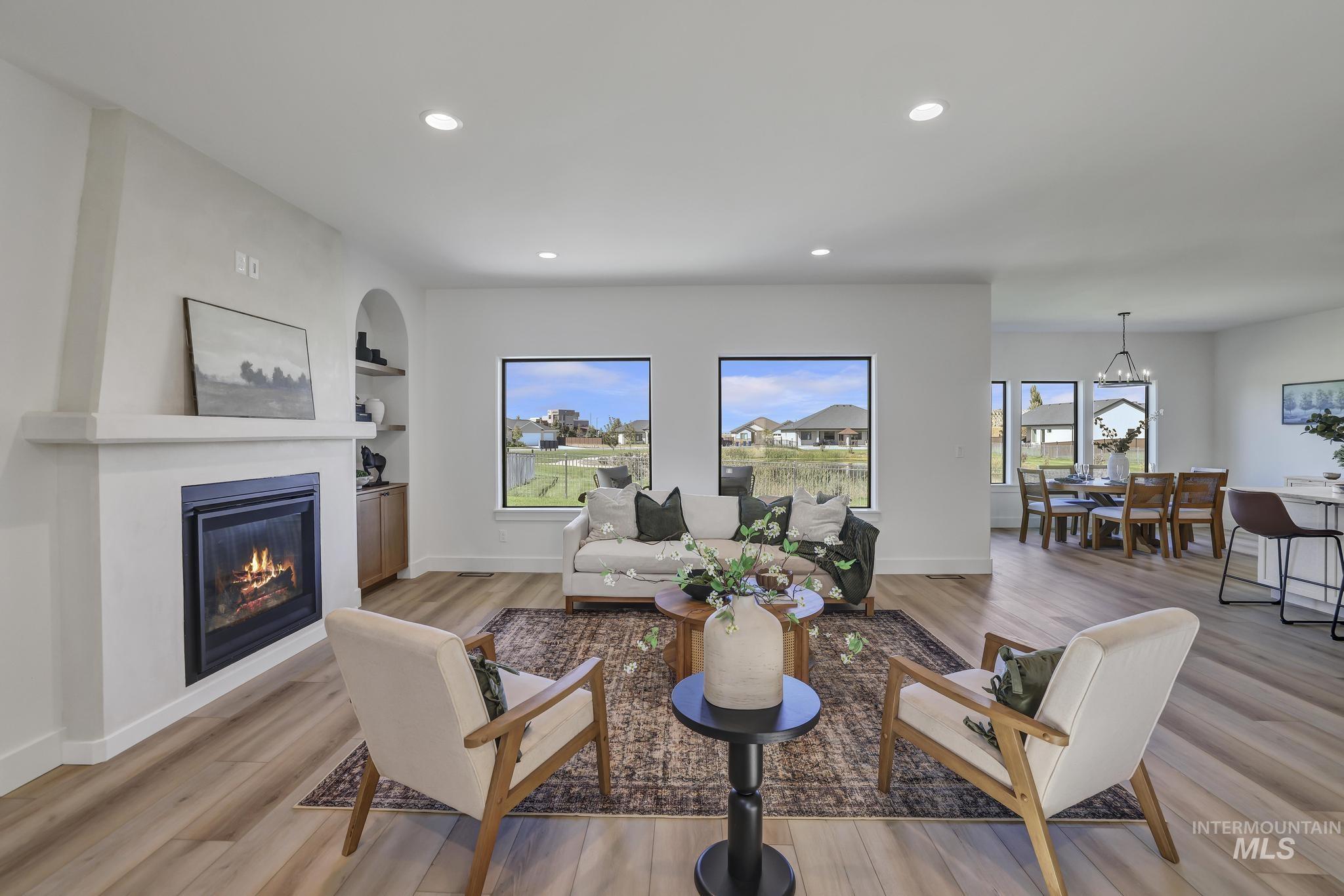 Living area with recessed lighting, built in shelves, light wood-type flooring, healthy amount of natural light, and a glass covered fireplace