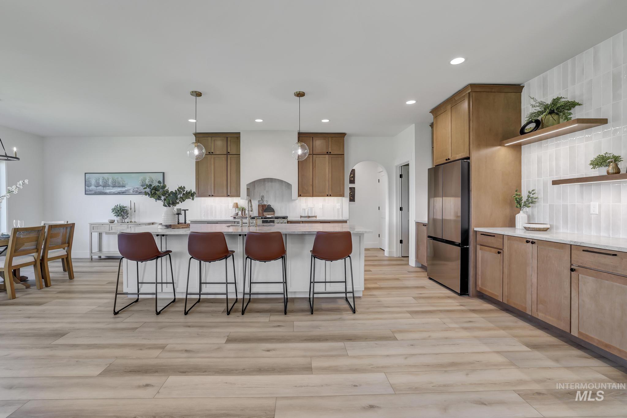 Kitchen featuring open shelves, backsplash, a breakfast bar area, arched walkways, and recessed lighting