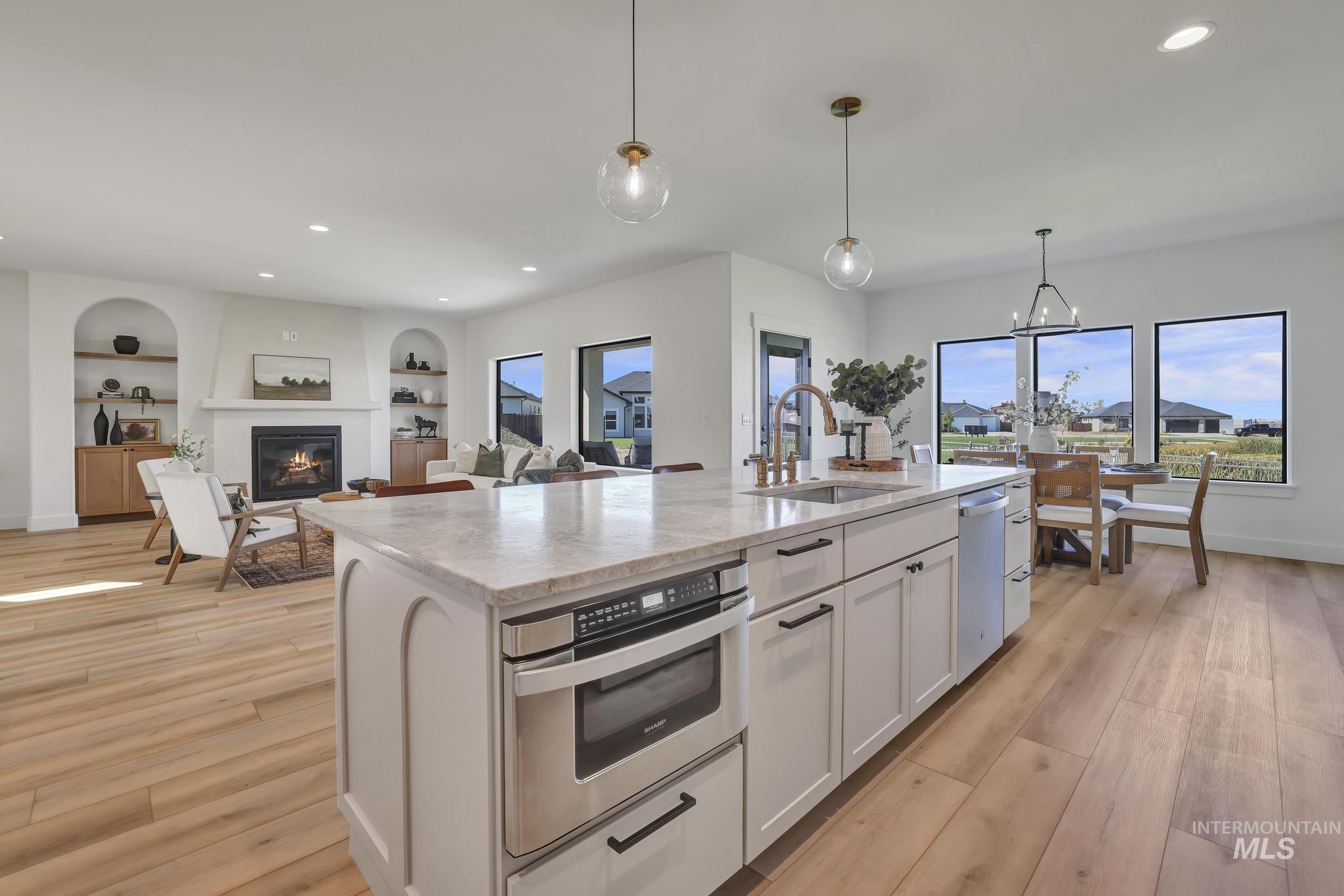 Kitchen featuring recessed lighting, decorative light fixtures, light wood-type flooring, light stone countertops, and appliances with stainless steel finishes