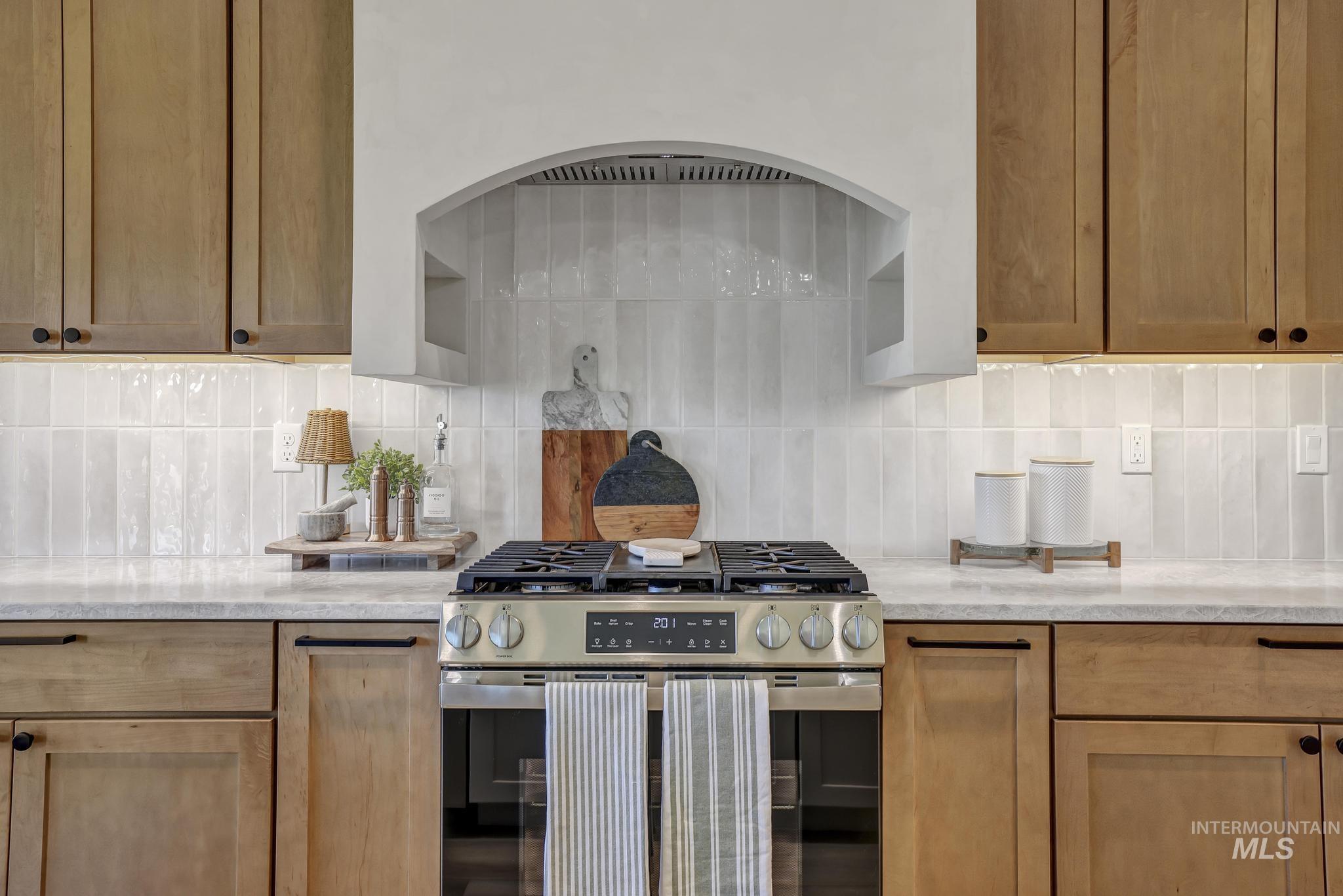 Kitchen with gas stove, tasteful backsplash, and light stone counters