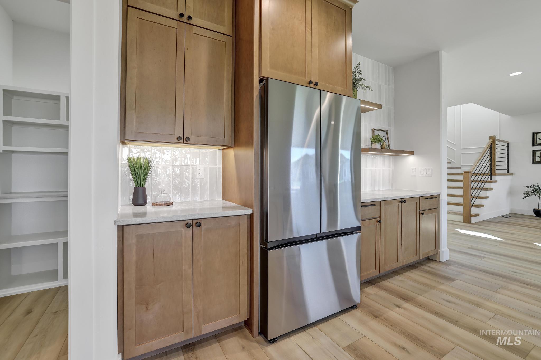 Kitchen featuring freestanding refrigerator, decorative backsplash, light wood-style flooring, light stone countertops, and recessed lighting