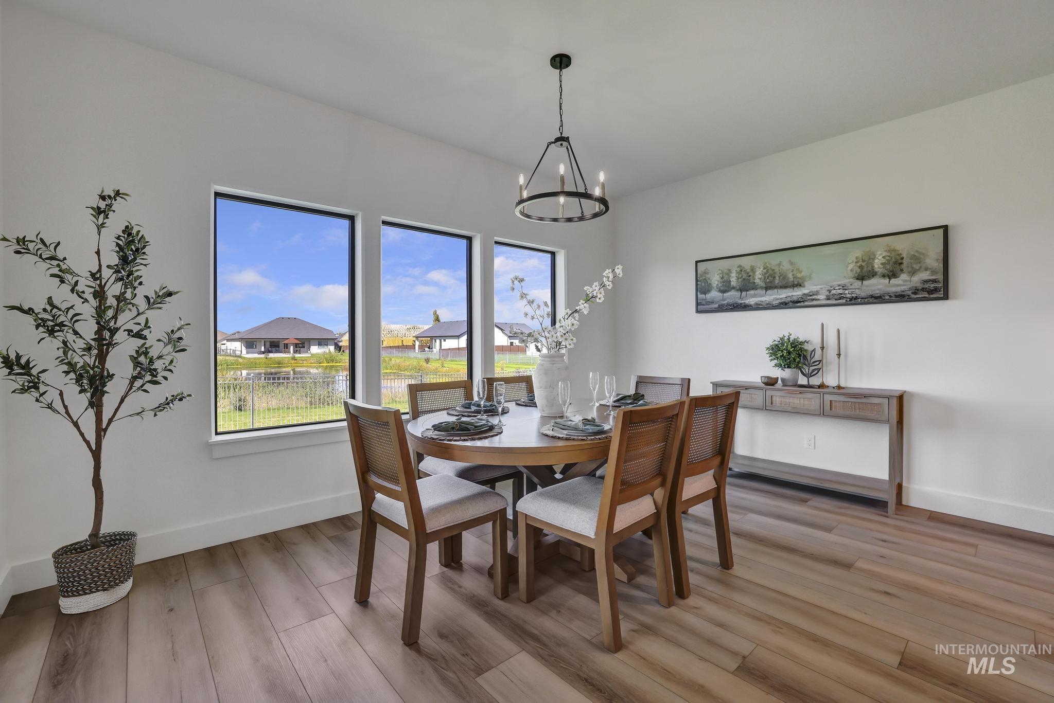 Dining room with light wood finished floors, a chandelier, and a residential view