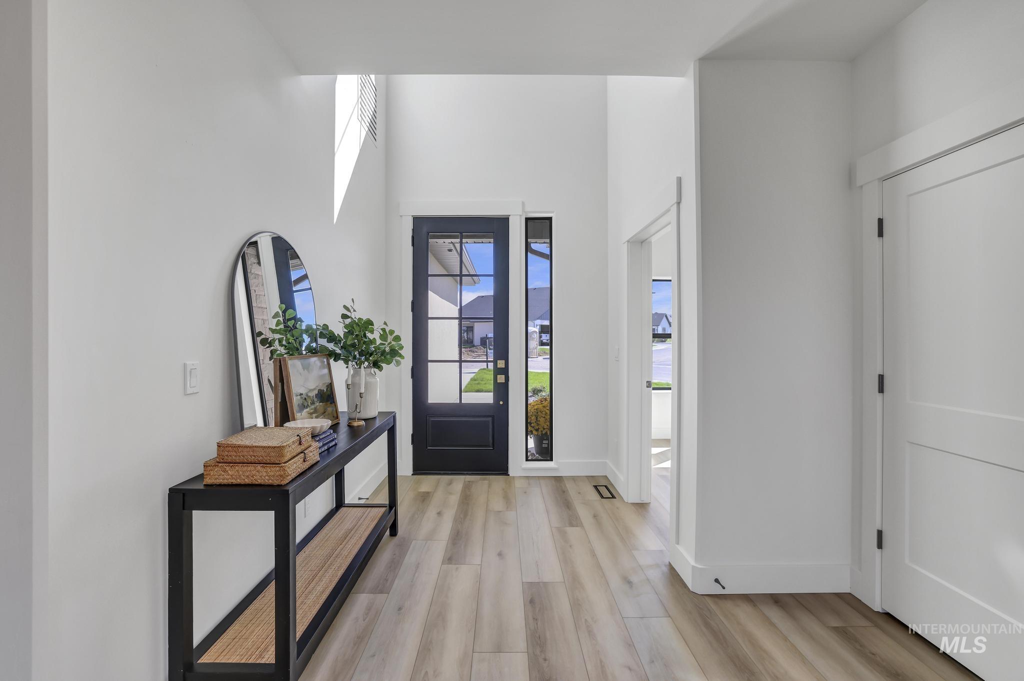 Foyer with healthy amount of natural light, light wood finished floors, and a towering ceiling