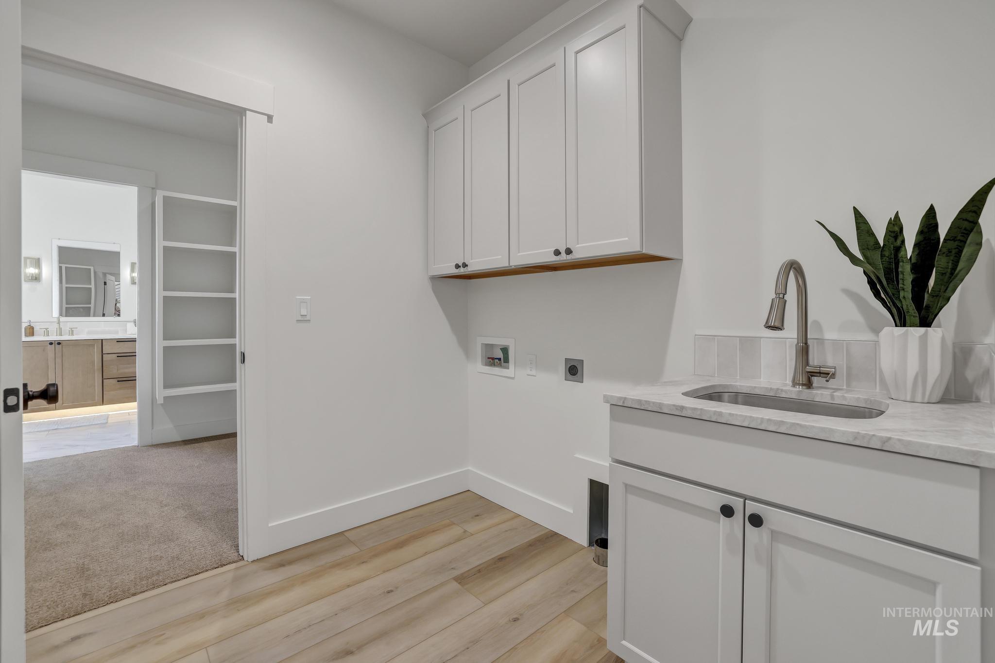 Laundry room featuring cabinet space, light wood-type flooring, washer hookup, electric dryer hookup, and light colored carpet
