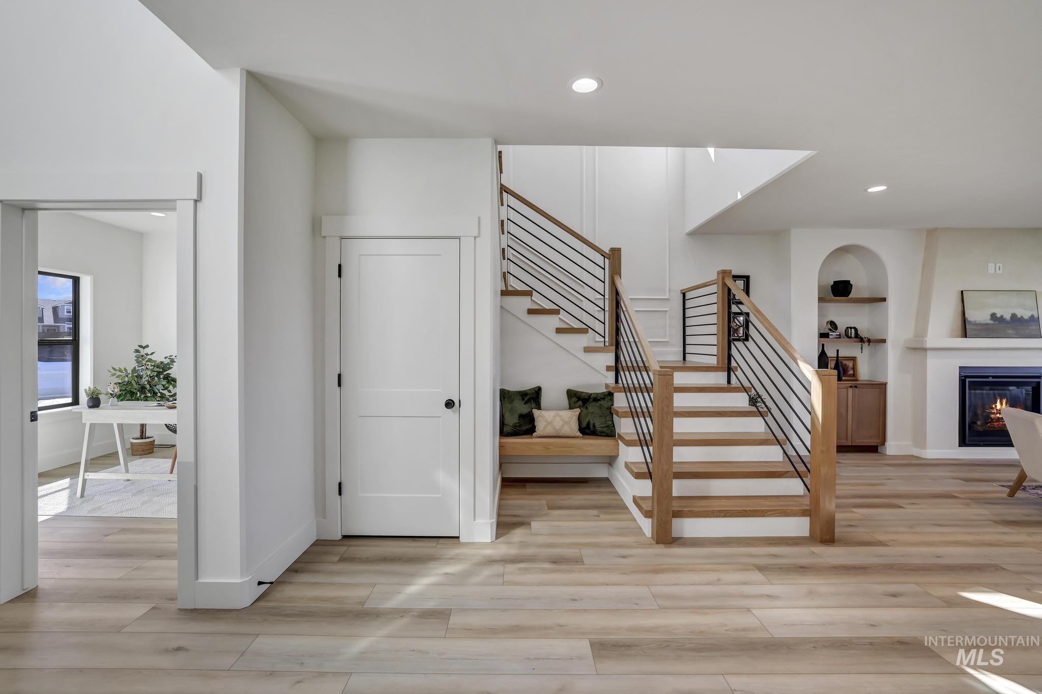 Entrance foyer with light wood-style floors, a glass covered fireplace, recessed lighting, and stairway