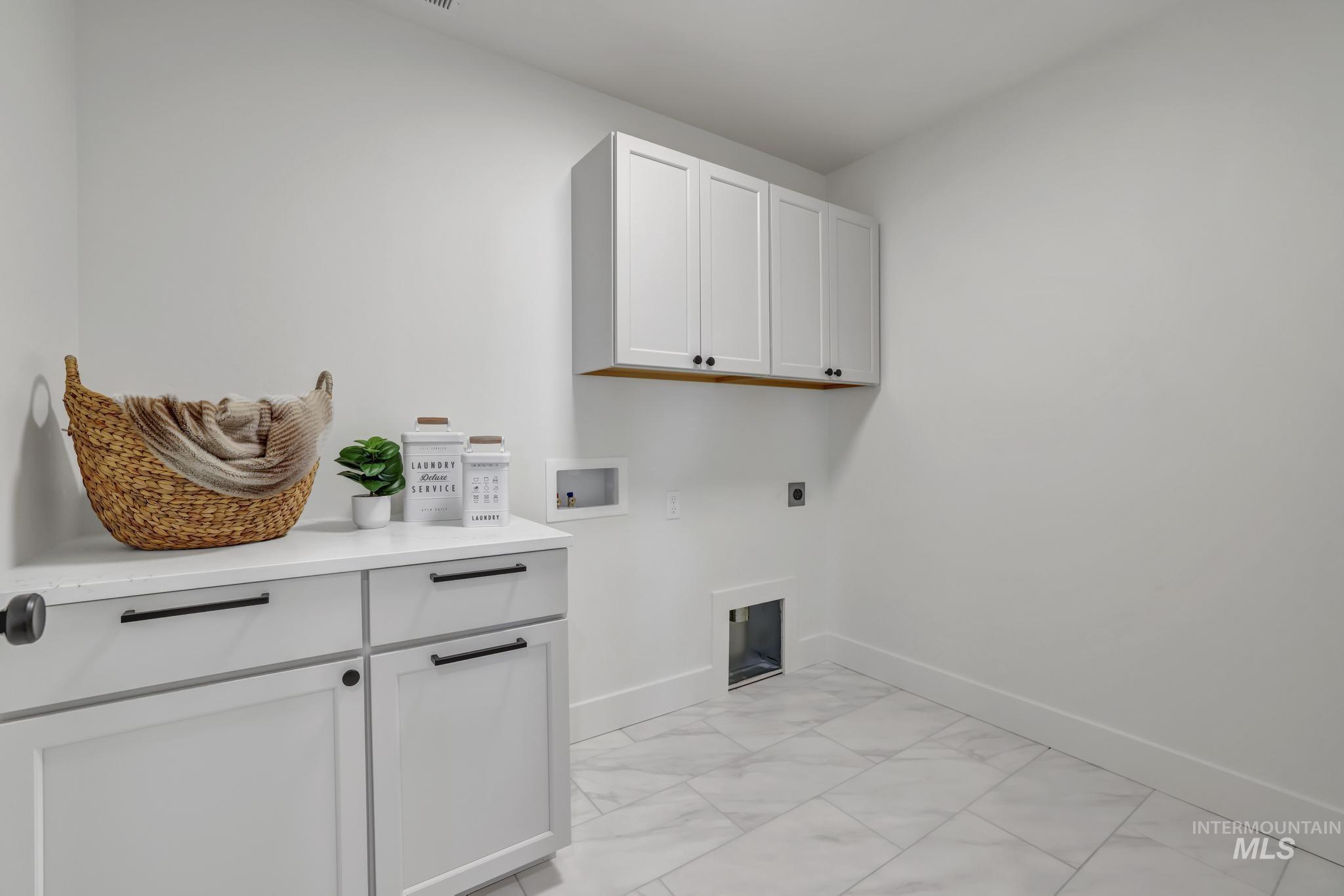 Laundry area with cabinet space, hookup for a washing machine, electric dryer hookup, and light marble finish floors