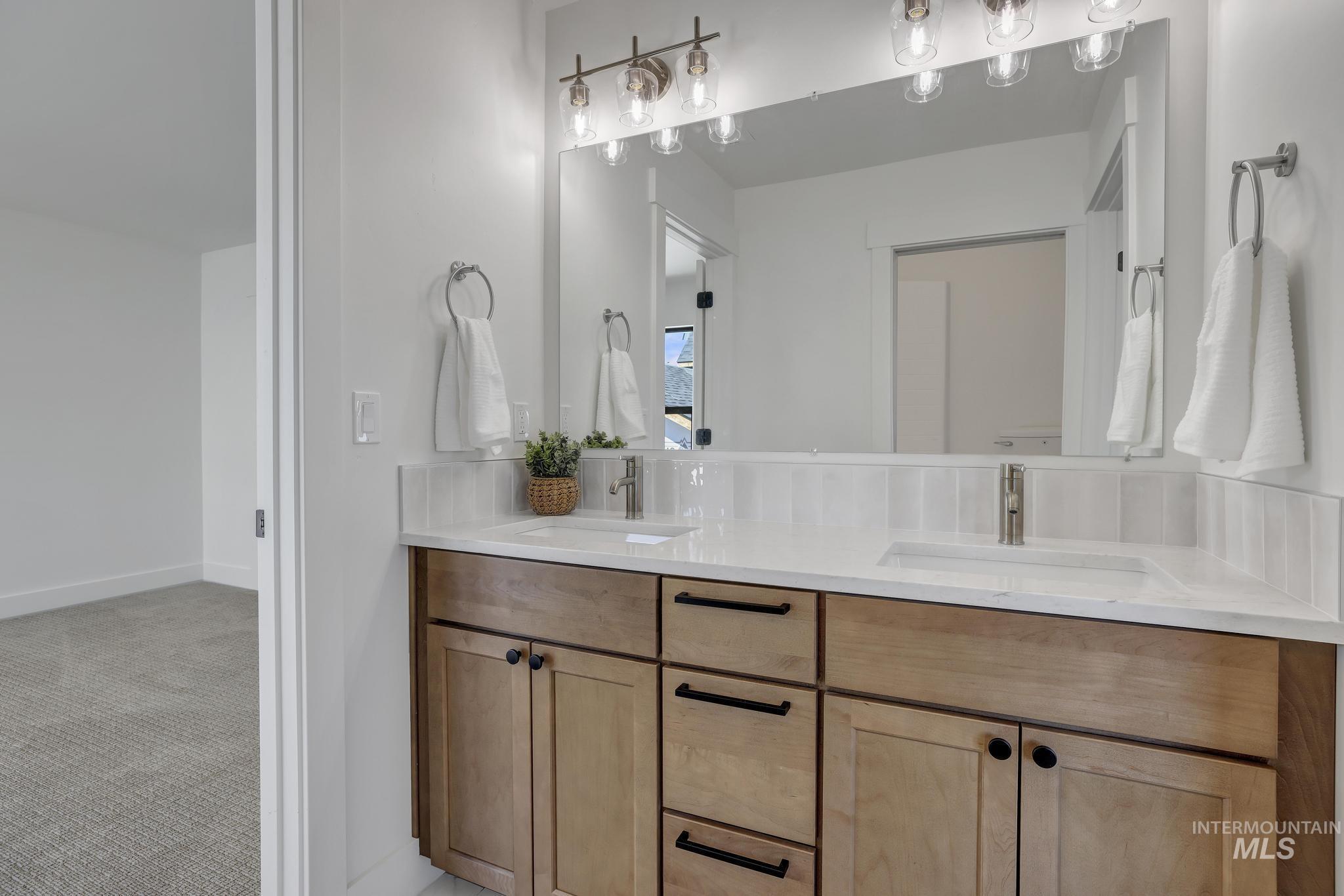 Full bath featuring double vanity and baseboards
