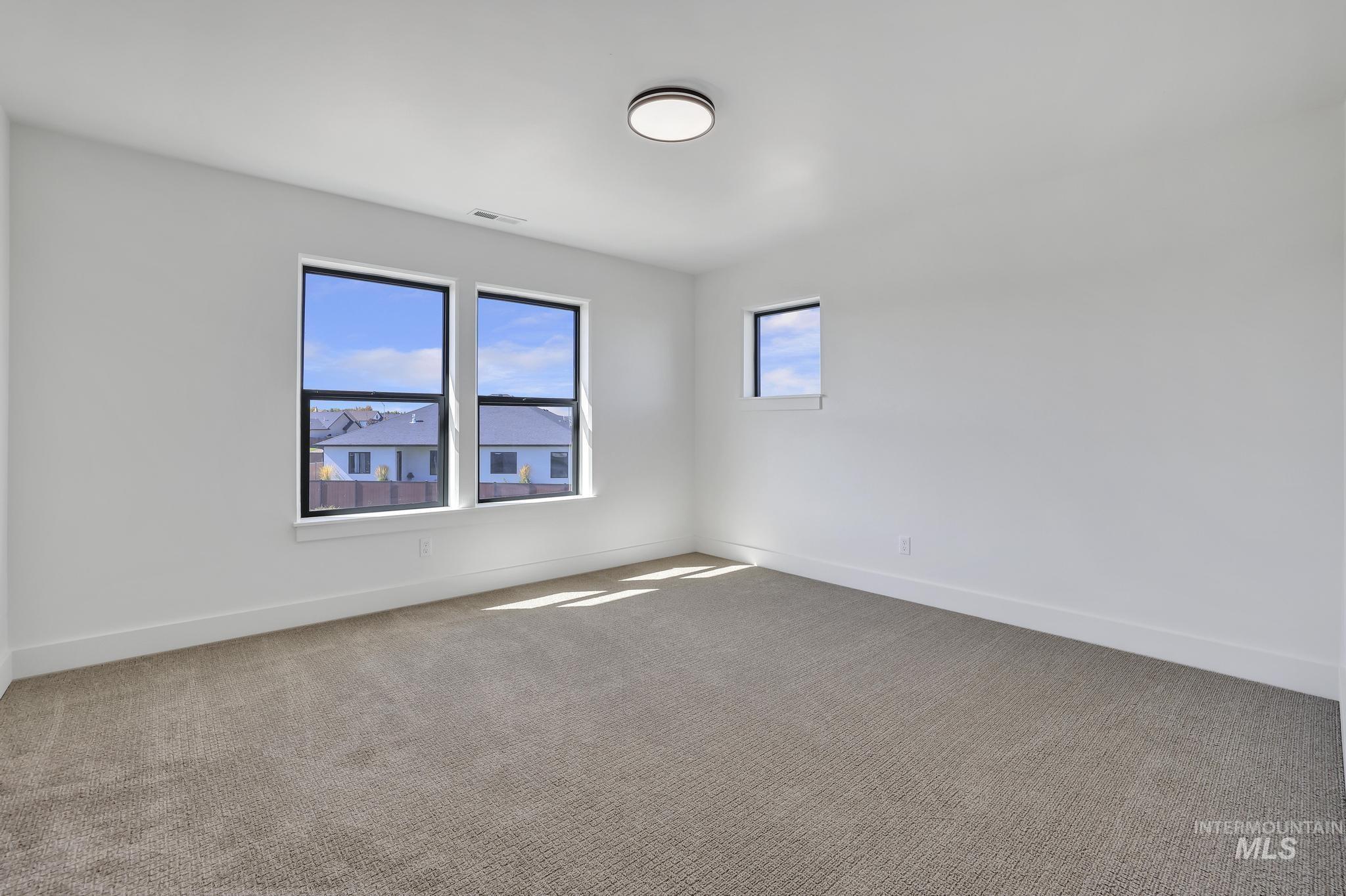 Empty room featuring light colored carpet and baseboards