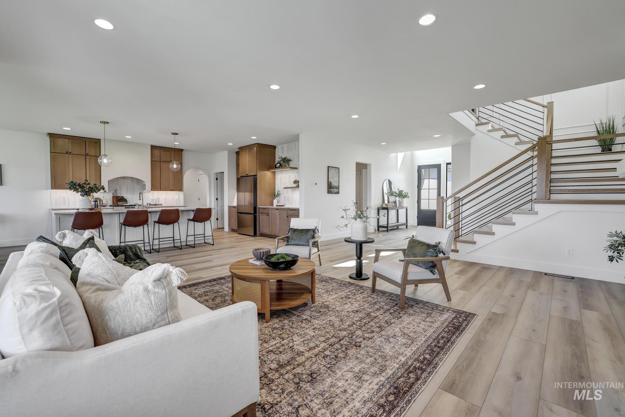 Living area with light wood-style floors, recessed lighting, stairway, and arched walkways