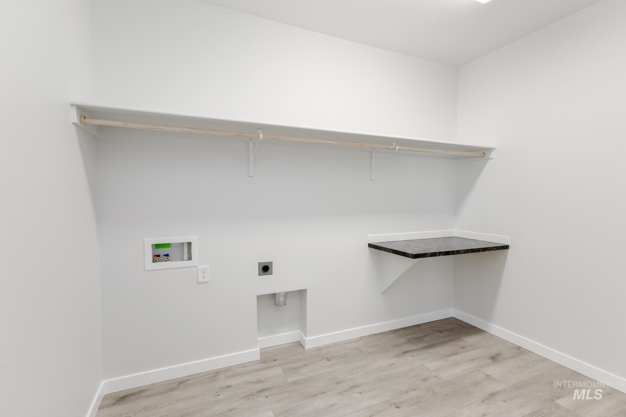 Washroom with hookup for a washing machine, electric dryer hookup, and light wood-type flooring