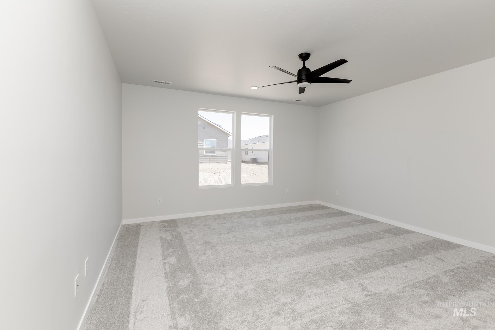 Carpeted empty room with a ceiling fan and baseboards
