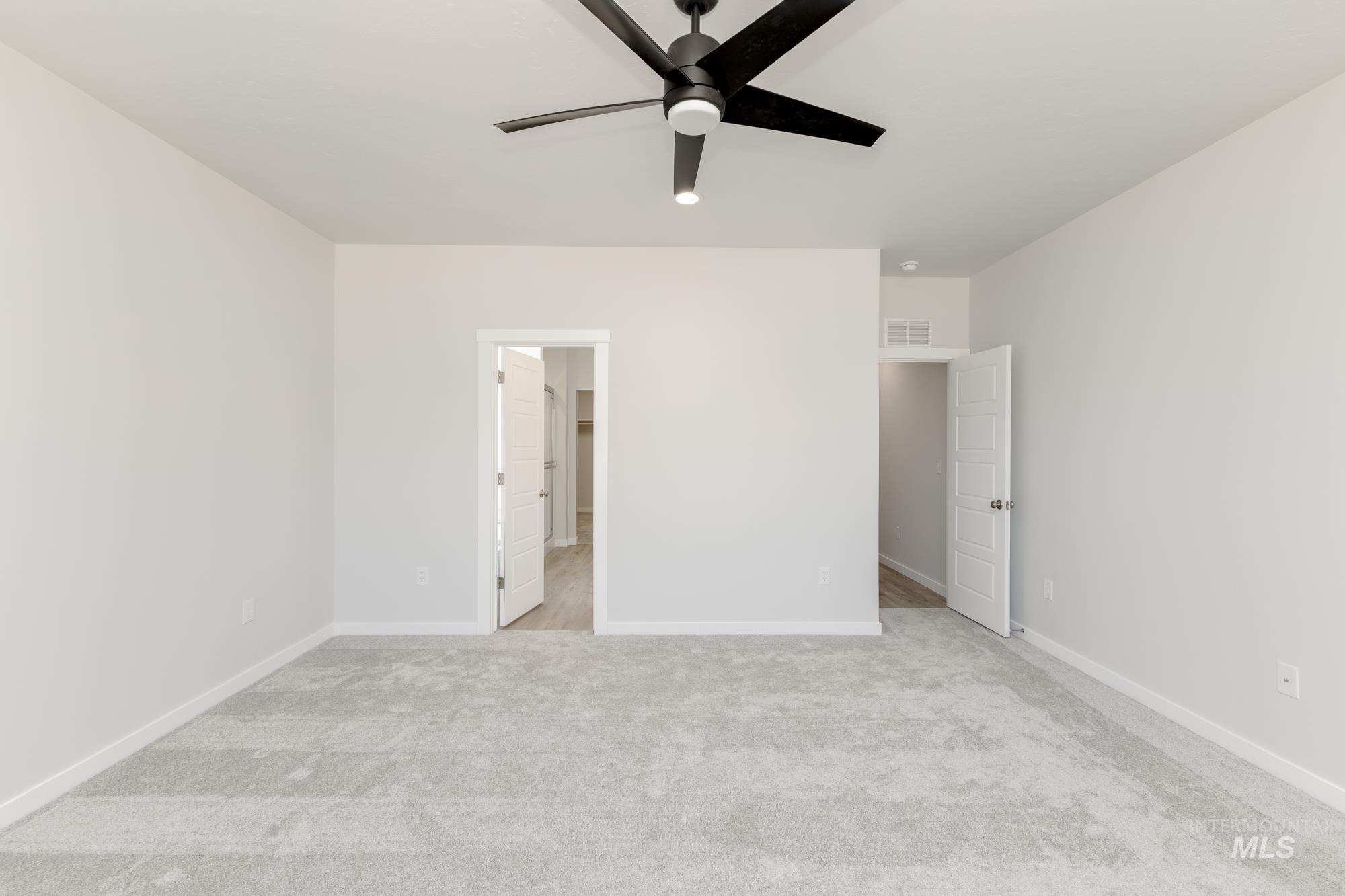 Unfurnished bedroom featuring light carpet, a spacious closet, and a ceiling fan