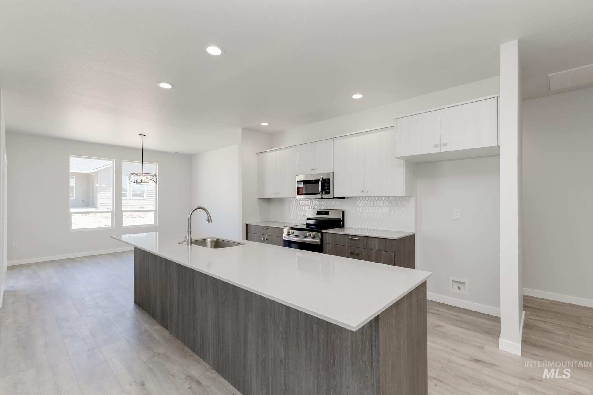 Kitchen with appliances with stainless steel finishes, white cabinets, light countertops, backsplash, and recessed lighting