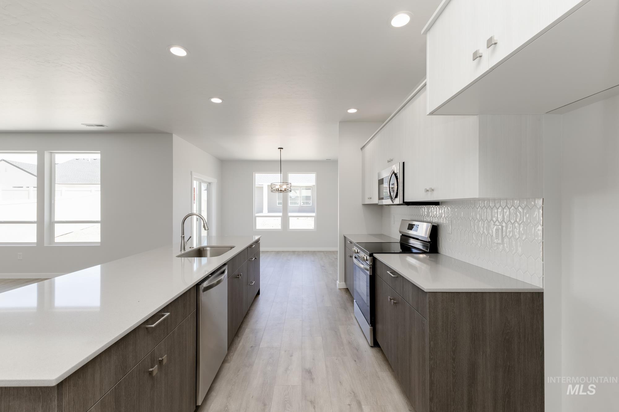 Kitchen featuring appliances with stainless steel finishes, modern cabinets, light wood-type flooring, white cabinets, and light countertops