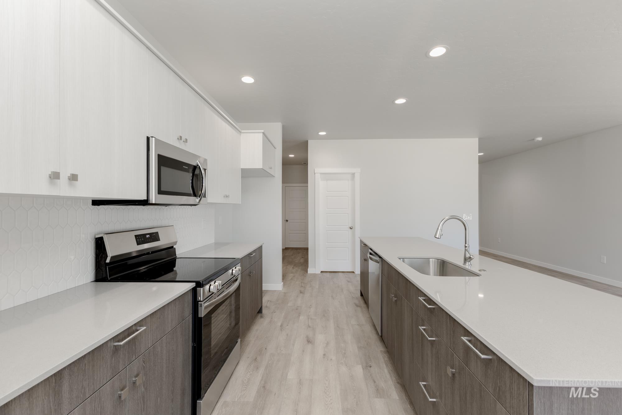 Kitchen featuring stainless steel appliances, white cabinets, tasteful backsplash, light wood-style flooring, and modern cabinets